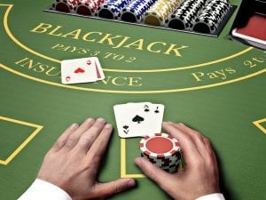 pair og hands on a blackjack table, holding casino chips 