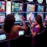 two women cheering in front of slot machines