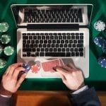a man placing poker chips near his laptop