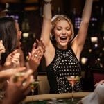 a girl cheering while sitting on a green casino table