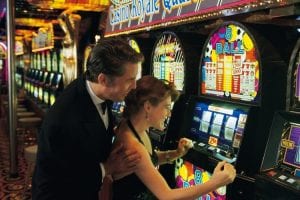 a man and a woman cheering while looking at a slot machine