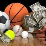 sports balls laying on the floor with a hand holding a couple of dollars