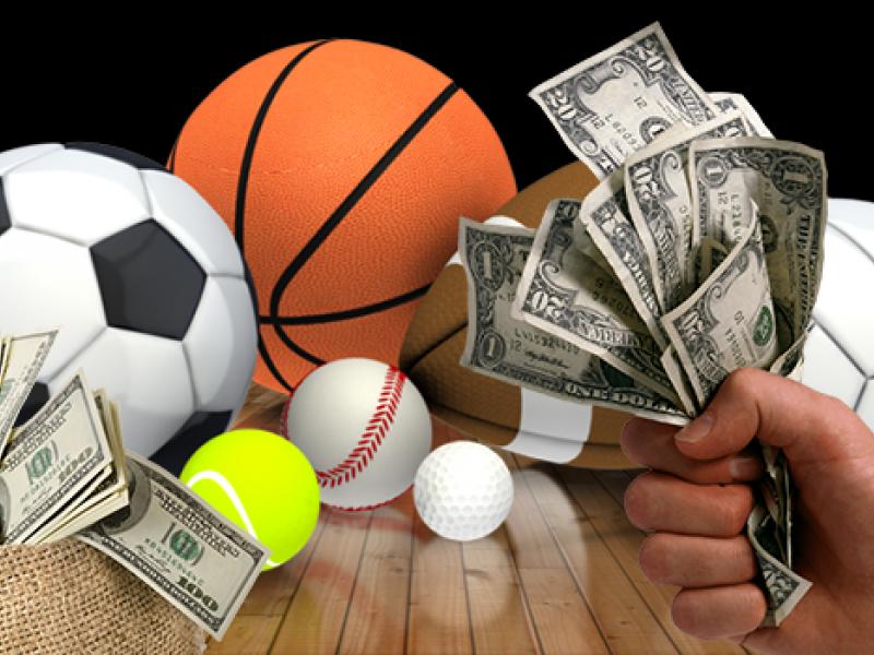 sports balls laying on the floor with a hand holding a couple of dollars